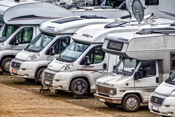 Aneinandergereihte Wohnmobile stehen auf einem Wohnmobilstellplatz