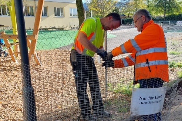 2 Mitarbeiter des Verbandsbauhofs beim Aufstellen der Laubkörbe