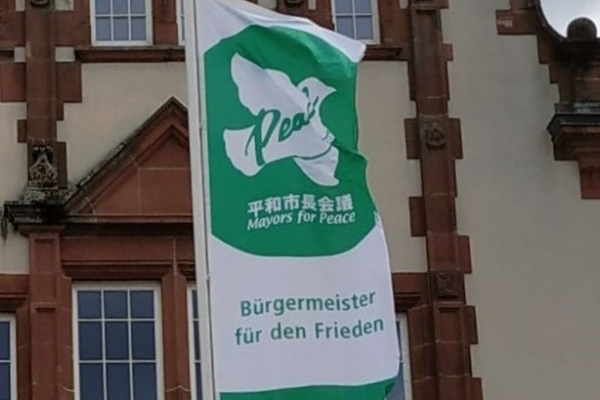 Eine grüne Flagge mit der Aufschrift "Bürgermeister für den Frieden" Eine grüne Flagge mit der Aufschrift "Bürgermeister für den Frieden"