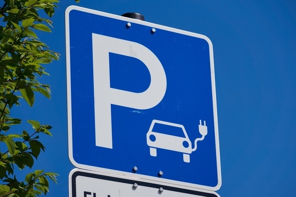 Blaues Schild mit weier Schrift und weier Zeichnunf eines Elektroautos