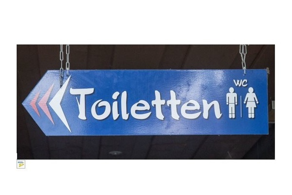 Blaues Hinweisschild in Pfeilform nach links mit weißer Aufschrift Toiletten/WC und Zeichnung Mann/Frau Blaues Hinweisschild in Pfeilform nach links mit weißer Aufschrift Toiletten/WC und Zeichnung Mann/Frau