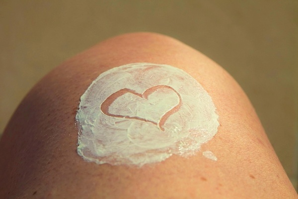 Haut, die sichtbar mit Sonnencreme eingeschmiert ist. In die Creme ist ein Herz gezeichnet. Haut, die sichtbar mit Sonnencreme eingeschmiert ist. In die Creme ist ein Herz gezeichnet.