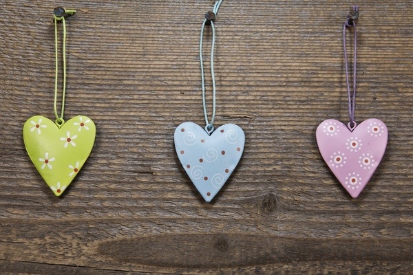 Drei bunte herzförmige Anhänger vor hölzernem Hintergrund Drei bunte herzförmige Anhänger vor hölzernem Hintergrund