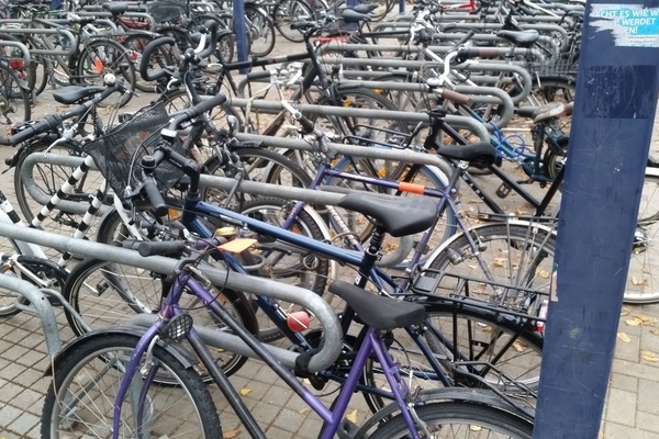 Viele Fahrräder abgestellt an Fahrradständern mit Anlehnbügel und doppelseitiger Radeinstellung Viele Fahrräder abgestellt an Fahrradständern mit Anlehnbügel und doppelseitiger Radeinstellung