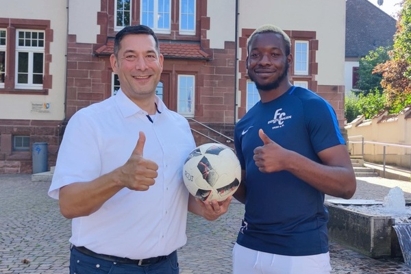 Foto v.l.n.r.: Bürgermeister Markus Hollemann und Christian Onuchukwu, der einen Fußball in seiner Hand hält