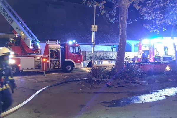 Zwei Löschfahrzeuge und eine Einsatzkraft vor einem Gebäude Zwei Löschfahrzeuge und eine Einsatzkraft vor einem Gebäude