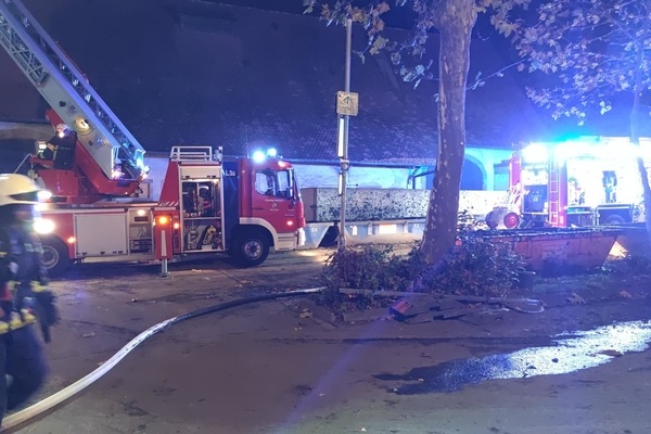 Zwei Löschfahrzeuge und eine Einsatzkraft vor einem Gebäude