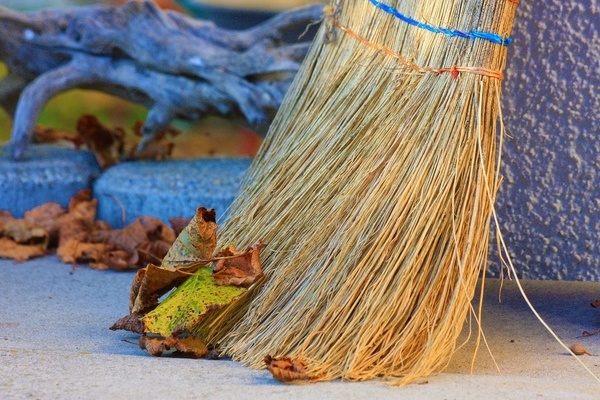 Herbstlaub auf einer Straße, ein Besen Herbstlaub auf einer Straße, ein Besen