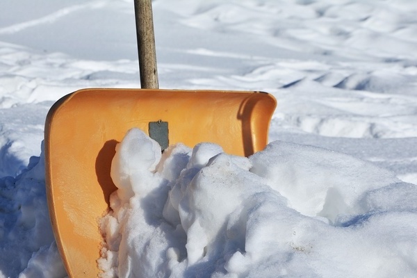 Weißer Schnee und eine orangefarbene Schneeschaufel Weißer Schnee und eine orangefarbene Schneeschaufel
