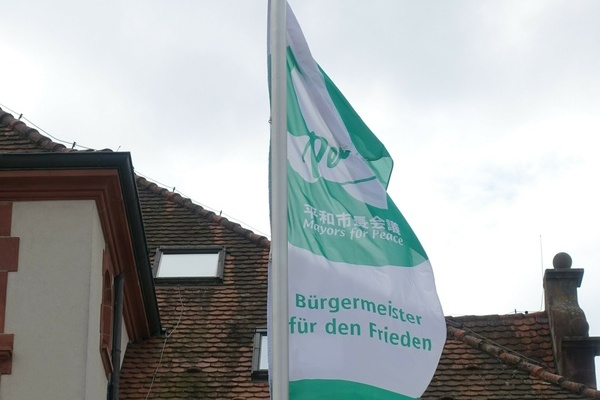 Die Flagge der Mayors for Peace weht vor dem Alten Rathaus in Denzlingen Die Flagge der Mayors for Peace weht vor dem Alten Rathaus in Denzlingen