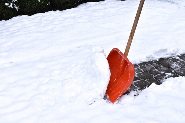 Beim Schneeräumen mit roter Schneeschaufel