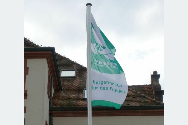 Die Flagge der „Mayors for Peace“ weht vor dem Alten Rathaus in Denzlingen. Foto: Melanie Lackner, Gemeinde Denzlingen. Die Flagge der „Mayors for Peace“ weht vor dem Alten Rathaus in Denzlingen. Foto: Melanie Lackner, Gemeinde Denzlingen.