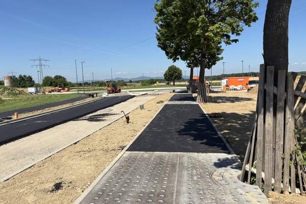 Bild: Ein Blick hinter die Absperrungen auf die Baustelle zur Erschlie&szlig;ung der Gewerbegebiete Langacker / Weidenacker. Die Asphaltierung ist in volem Gange. Foto: Gemeinde Denzlingen.