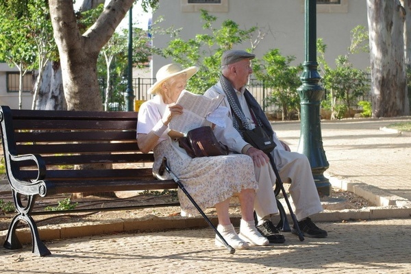 Zwei ltere Personen mit Gehstcken sitzen auf einer Ruhebank